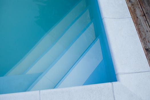 Elegant minimalist swimming pool with white stairs and clear water.